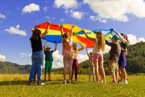 A group of children playing with a rainbow parachute