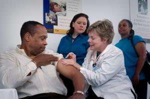 woman doctor giving a man a shot while nurses observe