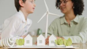craft paper houses and windmill in foreground with an adult and a child in the background